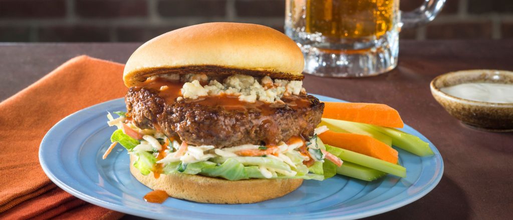A juicy Buffalo-Style Hot Sauce Burger topped with crumbled blue cheese, served with a side of celery root slaw.