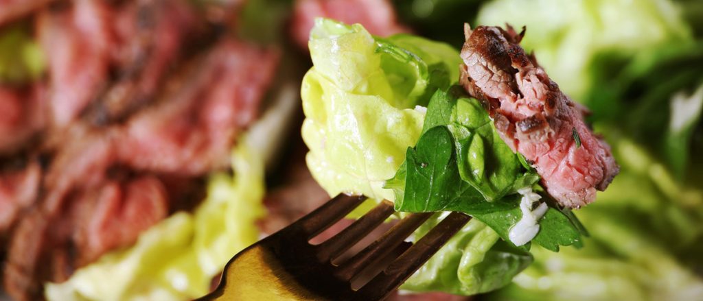 A vibrant steak and peach salad with mixed greens and a drizzle of lemon dressing.