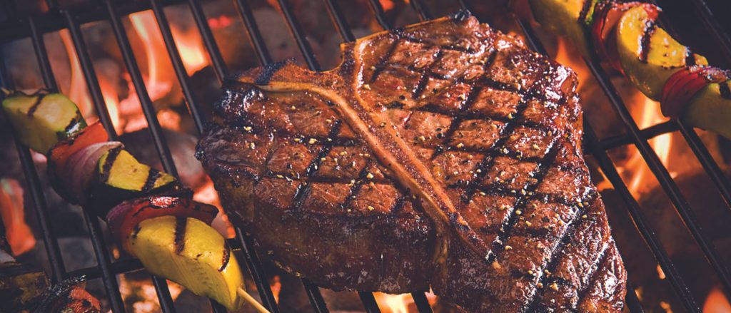 A beautifully seared porterhouse steak on a hot grill