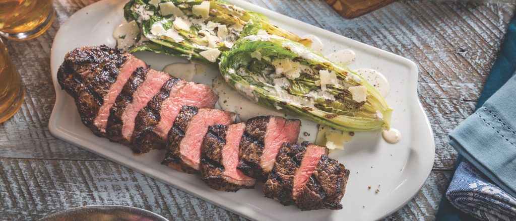 Juicy grilled strip steak with charred romaine hearts drizzled in creamy Caesar dressing.