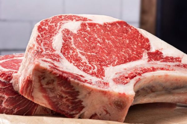 Certified Angus Beef bone-in ribeye steaks atop brown butcher paper.