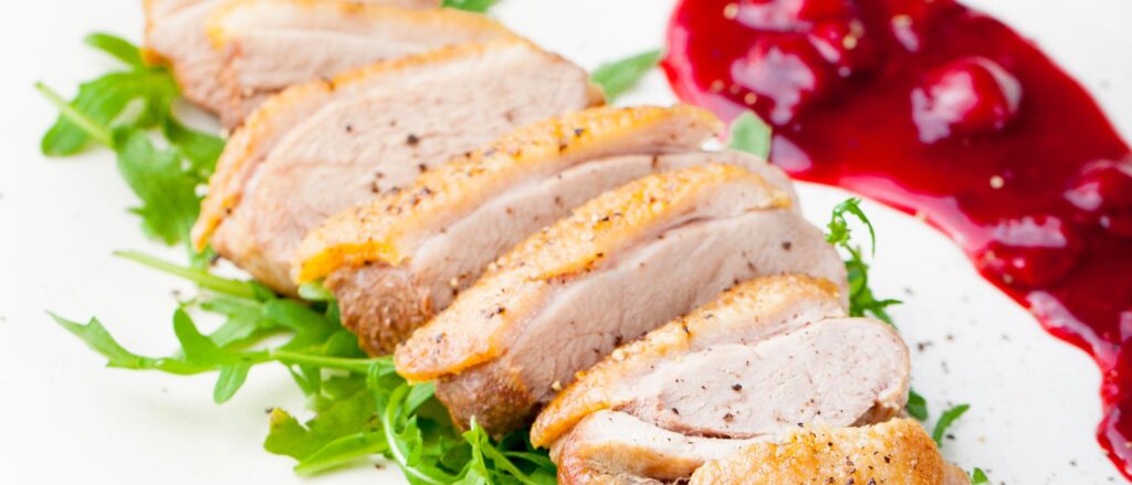 duck breast sliced and plated with cherry sauce