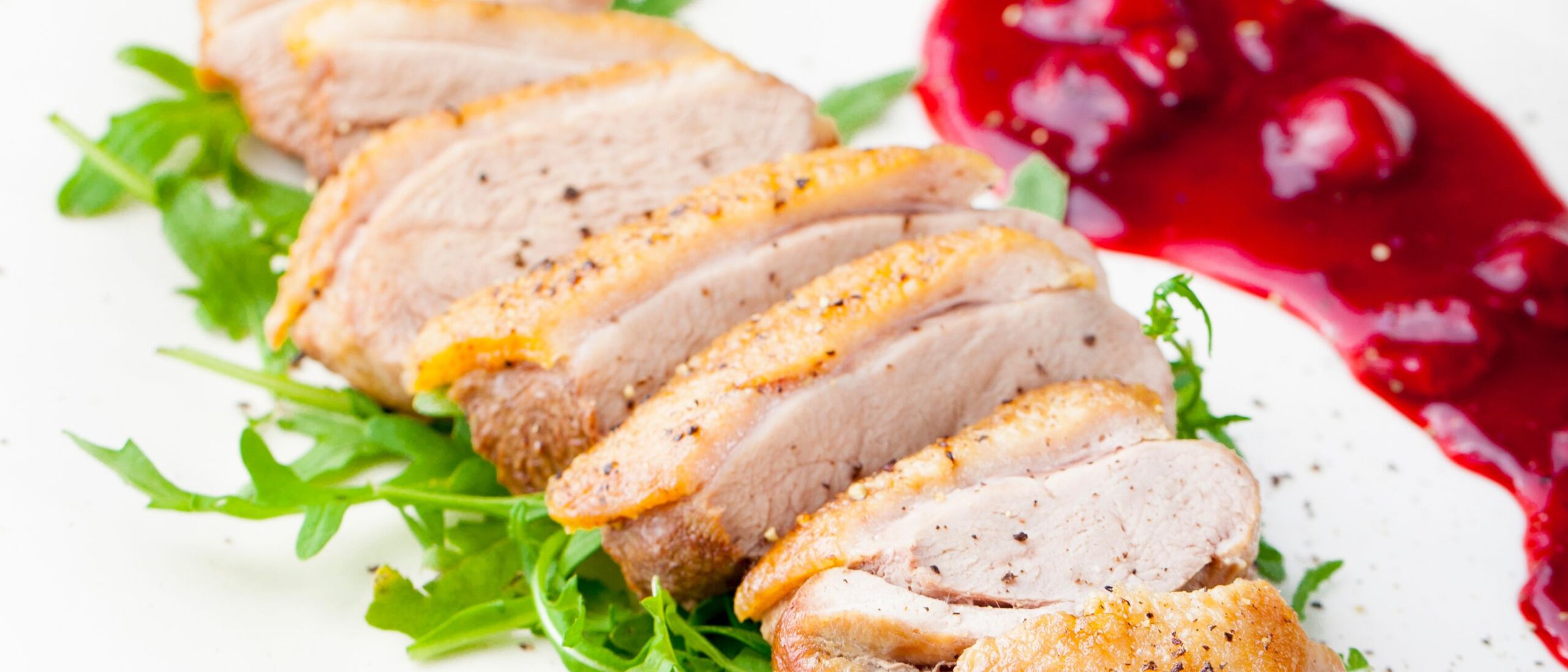 duck breast sliced and plated with cherry sauce